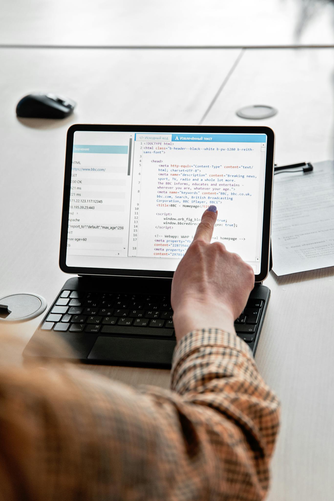 A person pointing at a code script on a tablet, emphasizing modern programming techniques.